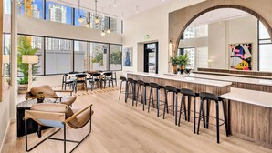 Un espace bar moderne avec des tabourets hauts, un comptoir et un grand miroir.