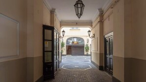 A corridor with a tiled floor, a closed door on the left, and a closed garage door in the distance. - Luxury Apartment for 5 with Terrace in Chiaia (Napoli)