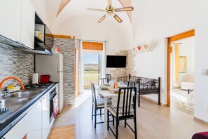 Una cocina moderna con comedor, televisor montado en la pared y balcón con vistas.