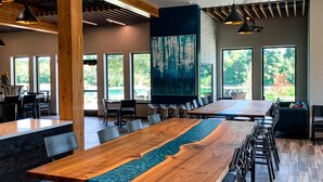 A modern dining area with a long wooden table, black metal chairs, and pendant lighting.