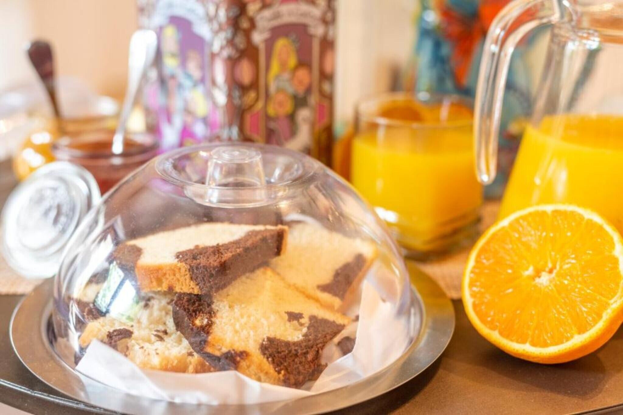 Ein Frühstückstisch mit Glaskuppel, einem Karaffee und einem Glas Orangensaft.