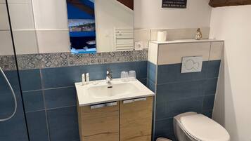 Une salle de bain avec un lavabo, un miroir et des toilettes.