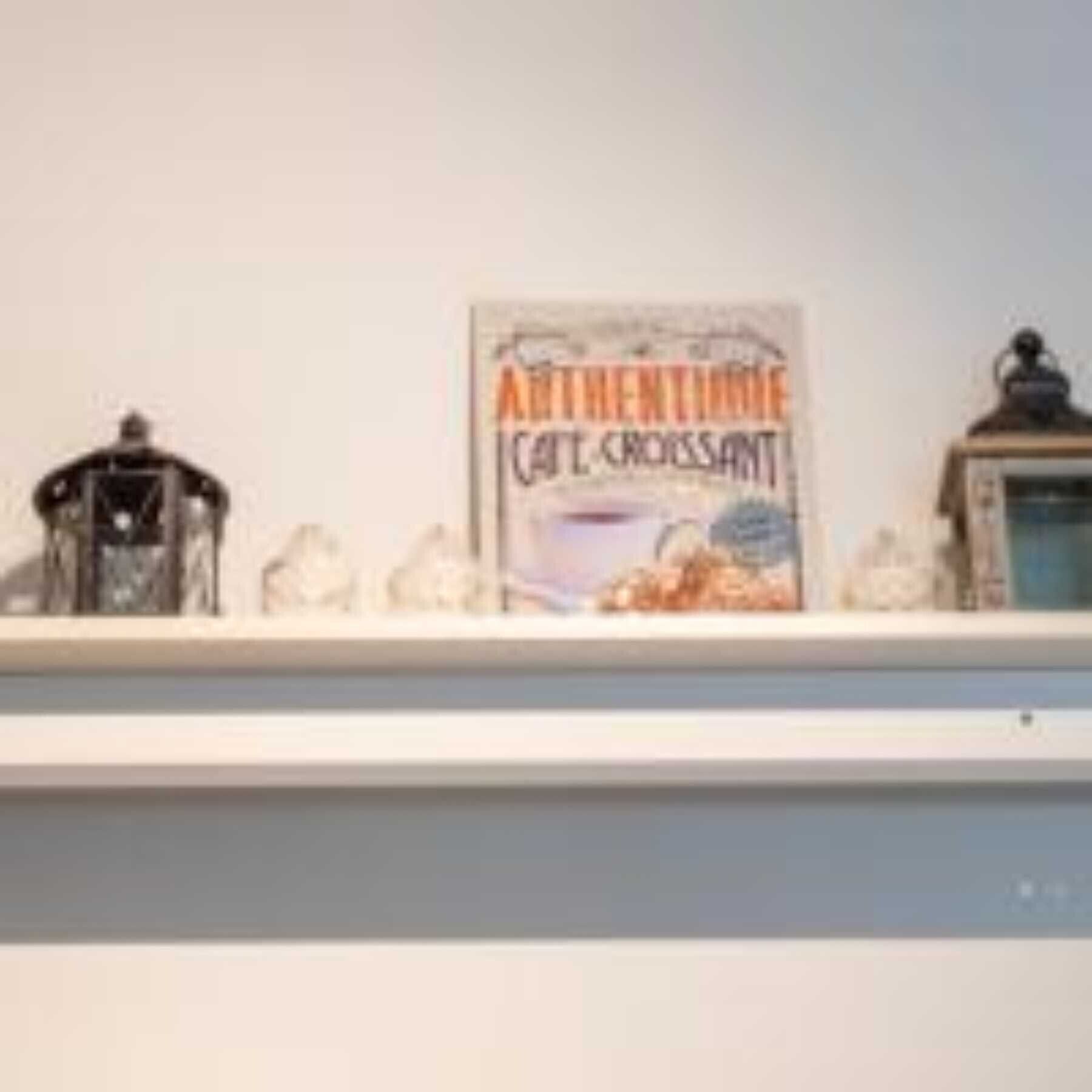A shelf with a box of 'Authentic Cafe Croissant' and two decorative items.