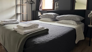A bedroom with a bed, a wardrobe, a mirror, and a window.
