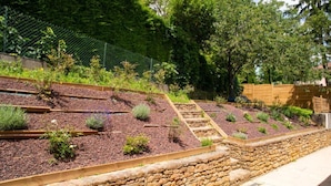 A garden with raised beds, a stone retaining wall, and a wooden fence.