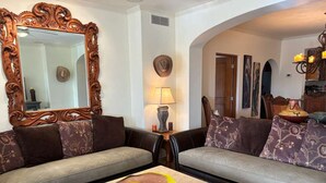 A living room with a large ornate mirror, two sofas with patterned cushions, a small table with a bowl, a lamp, and a chandelier. - Beautifully Maintained 2-bed Condo in Las Mañanitas (San José del Cabo)