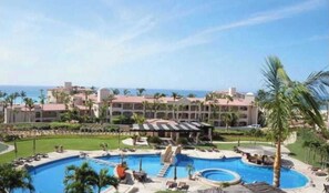 Un resort con una amplia piscina, varias edificaciones y palmeras.