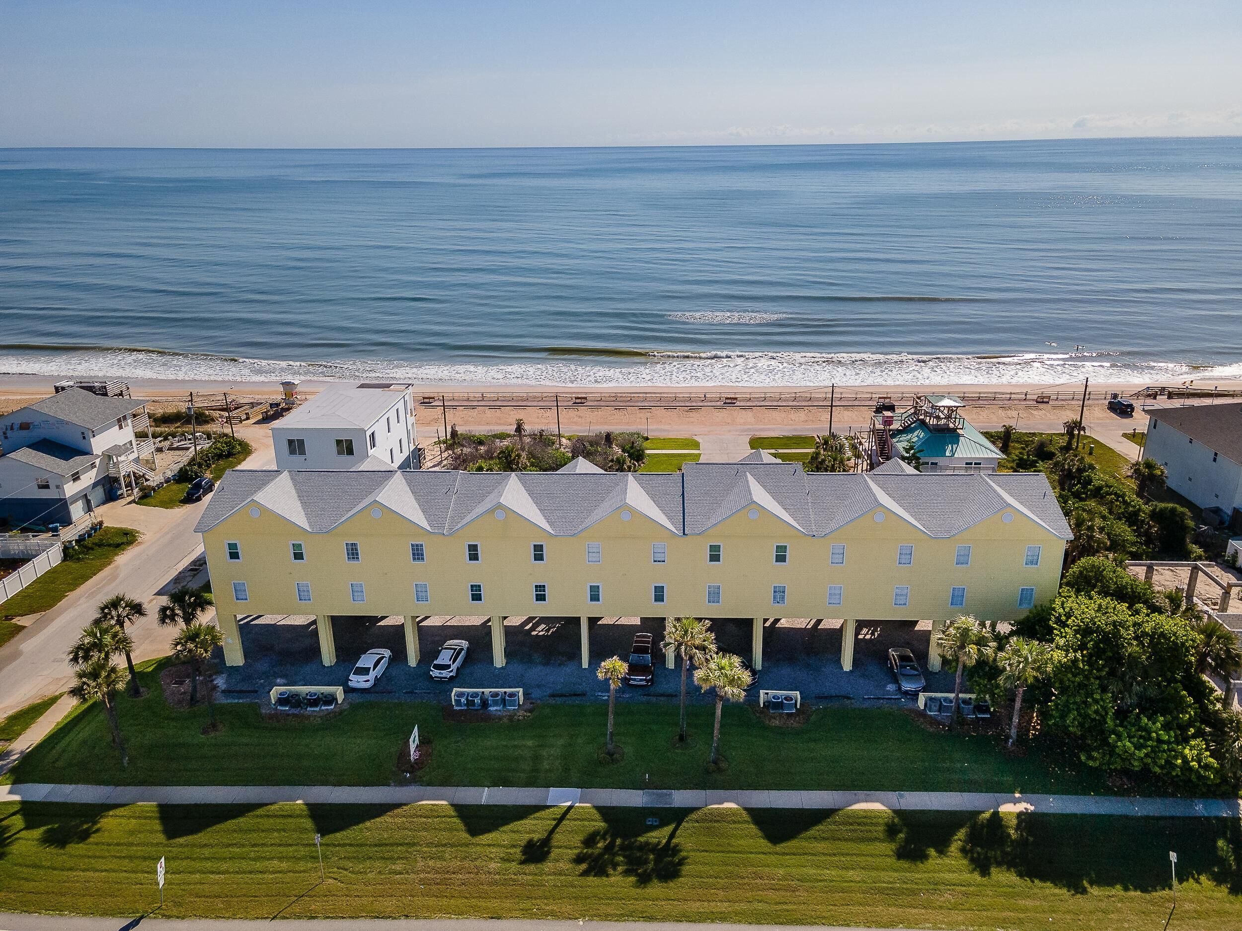 Un hotel costero con edificios de varios pisos, estacionamiento y vista a la playa.