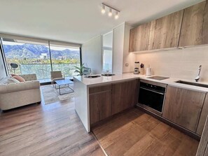A modern kitchen with wooden cabinets, a built-in oven, and a large island with a sink.