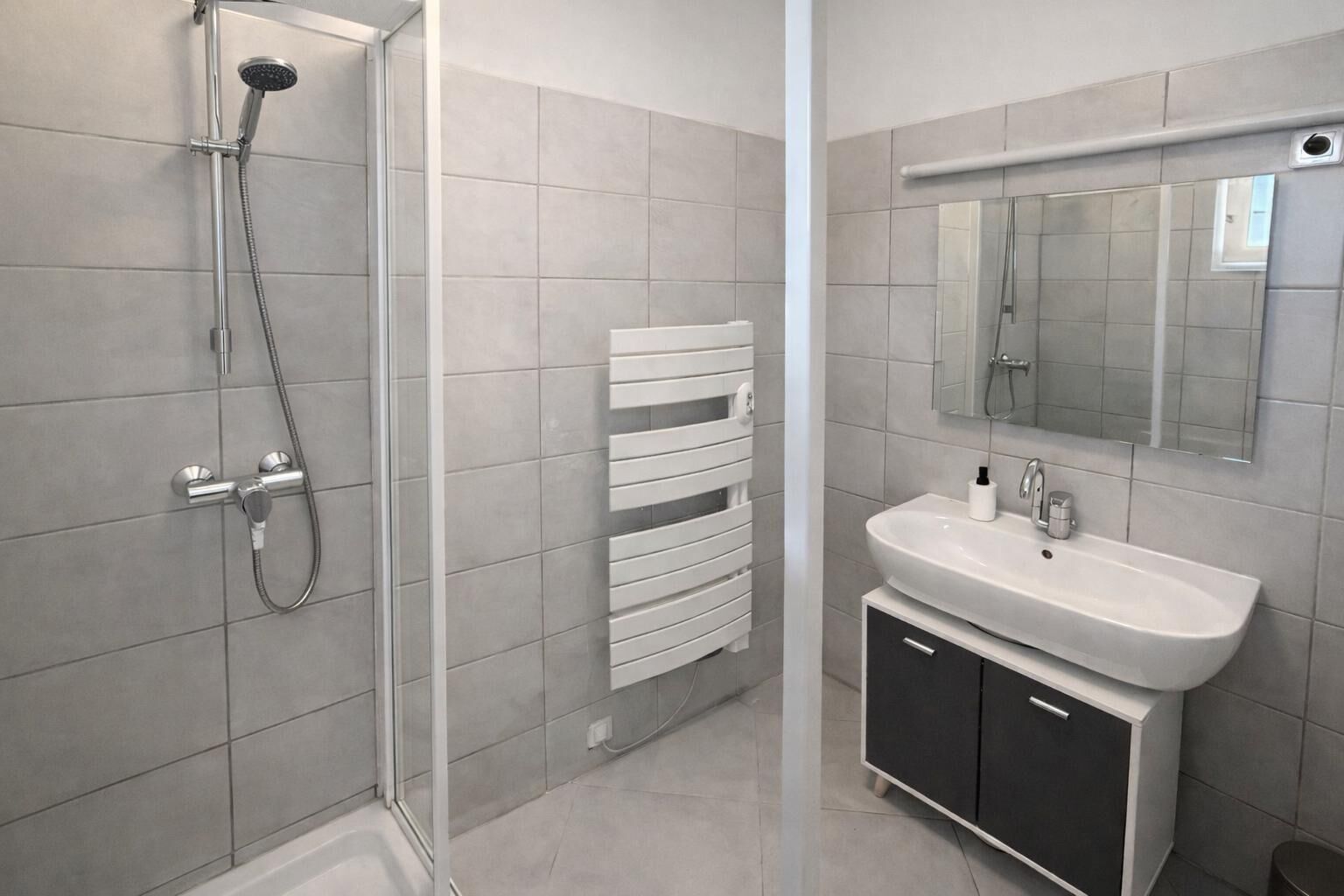 Une salle de bain moderne équipée d’une douche, d’un lavabo et d’un porte-serviettes.