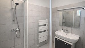 Ein modernes Badezimmer mit Dusche, Waschbecken und Handtuchhalter.