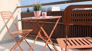 Ein Balkon mit Tisch, Stühlen und einem Blumentopf.