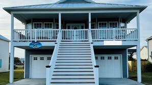 A two-story building with a balcony, a staircase leading to the entrance, and a garage. - Surf City Ocean View - 4-min Walk to Beach - Walk to Restaurants/Bars (Surf City)