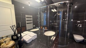A modern bathroom with two sinks, a glass shower enclosure, a toilet, and a towel rack. - Center Park Apartment (Interlaken)