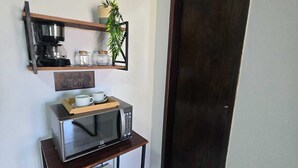 A compact kitchenette with a coffee maker, microwave, and small refrigerator. - Alex Sandro (Rio das Ostras)