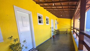A corridor with yellow walls, wooden ceiling beams, and potted plants. - Alex Sandro (Rio das Ostras)