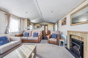 Ein gemütliches Wohnzimmer mit Sofas, einem Couchtisch, einem Kamin und Blick auf die Küche.