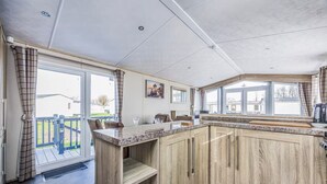 A kitchen with wooden cabinets, a marble countertop, and a view of the outdoors. - Lovely Lakeside Holiday Park Home  - Pass the Keys (Chichester)