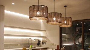 A modern kitchen with a central island, pendant lighting, and a checkered floor.