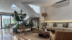 A modern living room with a checkered floor, a sofa, a coffee table, and a large plant.