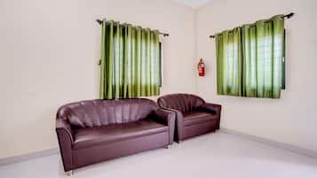 A room with two leather sofas, a fire extinguisher, and green curtains.