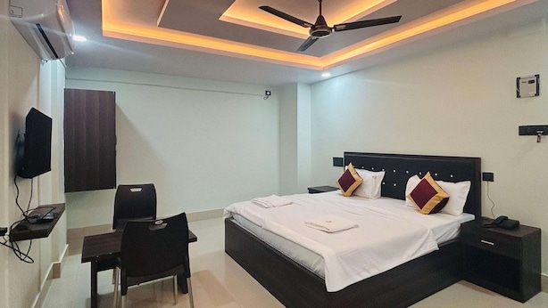 Habitación de hotel con cama, escritorio, silla, ventilador de techo y aire acondicionado.
