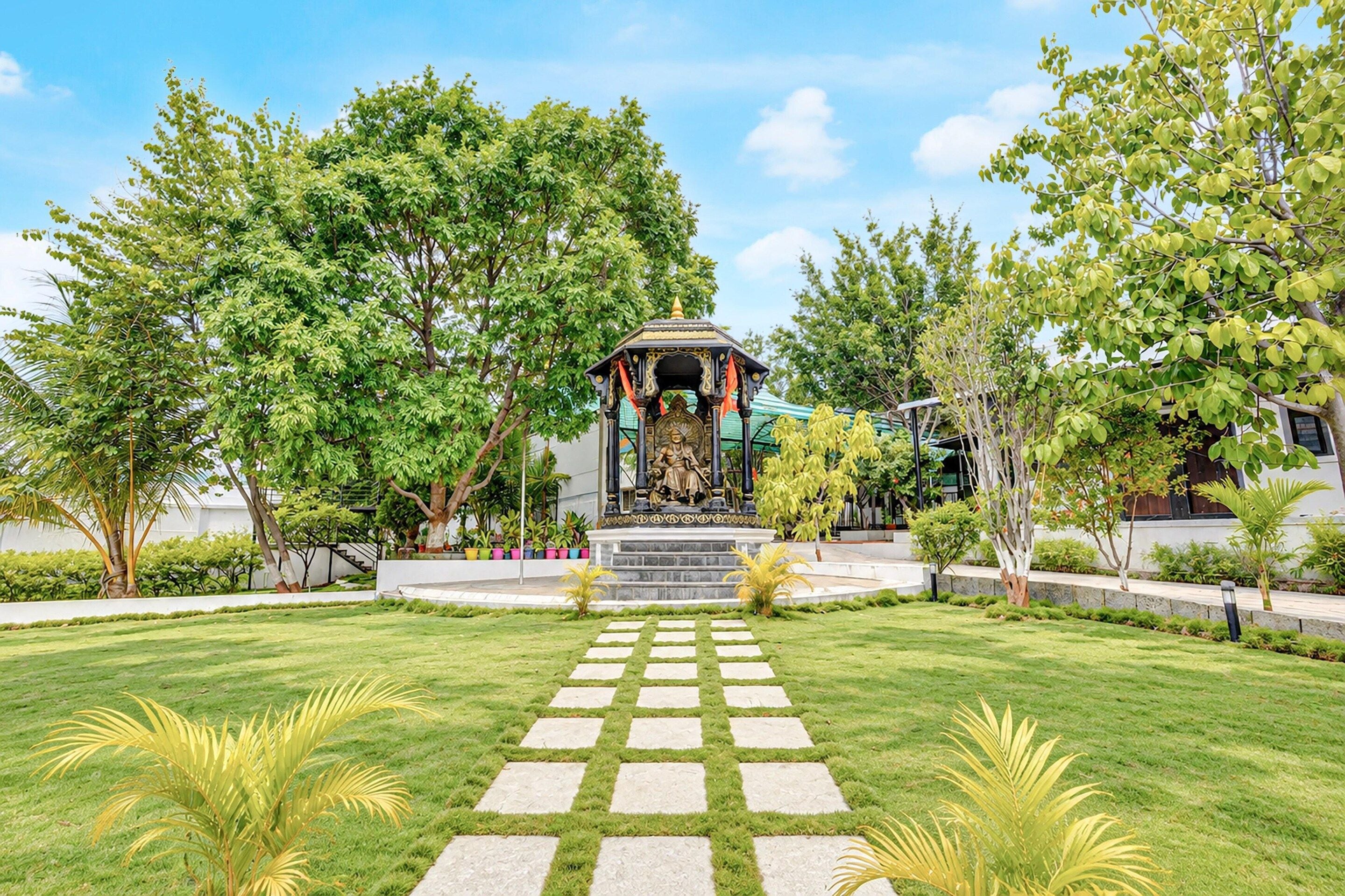 A garden with a central gazebo, surrounded by well-maintained grass and trees.