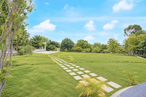 A well-maintained lawn with a geometric stone pathway leading to a white structure. - Townhouse Oak Phaltan Shivjal City (Phaltan)