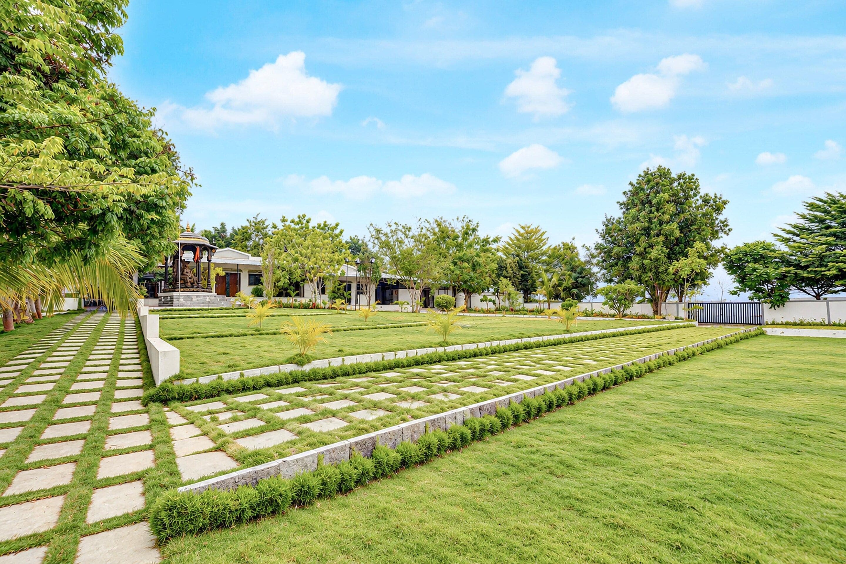 A landscaped garden with a paved walkway, neatly trimmed grass, and a variety of trees.