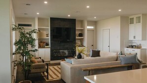 A modern living room with a fireplace, sofa, and dining area.