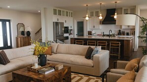 A modern kitchen with white cabinets, a central island, and pendant lighting.
