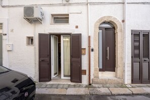 A building with a white facade, a black car parked in front, and a number '23' on the wall. - GuestHost - Comfy Studio Apartment with Terrace (Monopoli)
