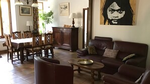 A living room with a brown leather sofa, a dining table with chairs, a cabinet, and a painting on the wall. - Holiday Home "Gîte for 6 People" with Private Terrace and Wi-Fi (La Chapelle)