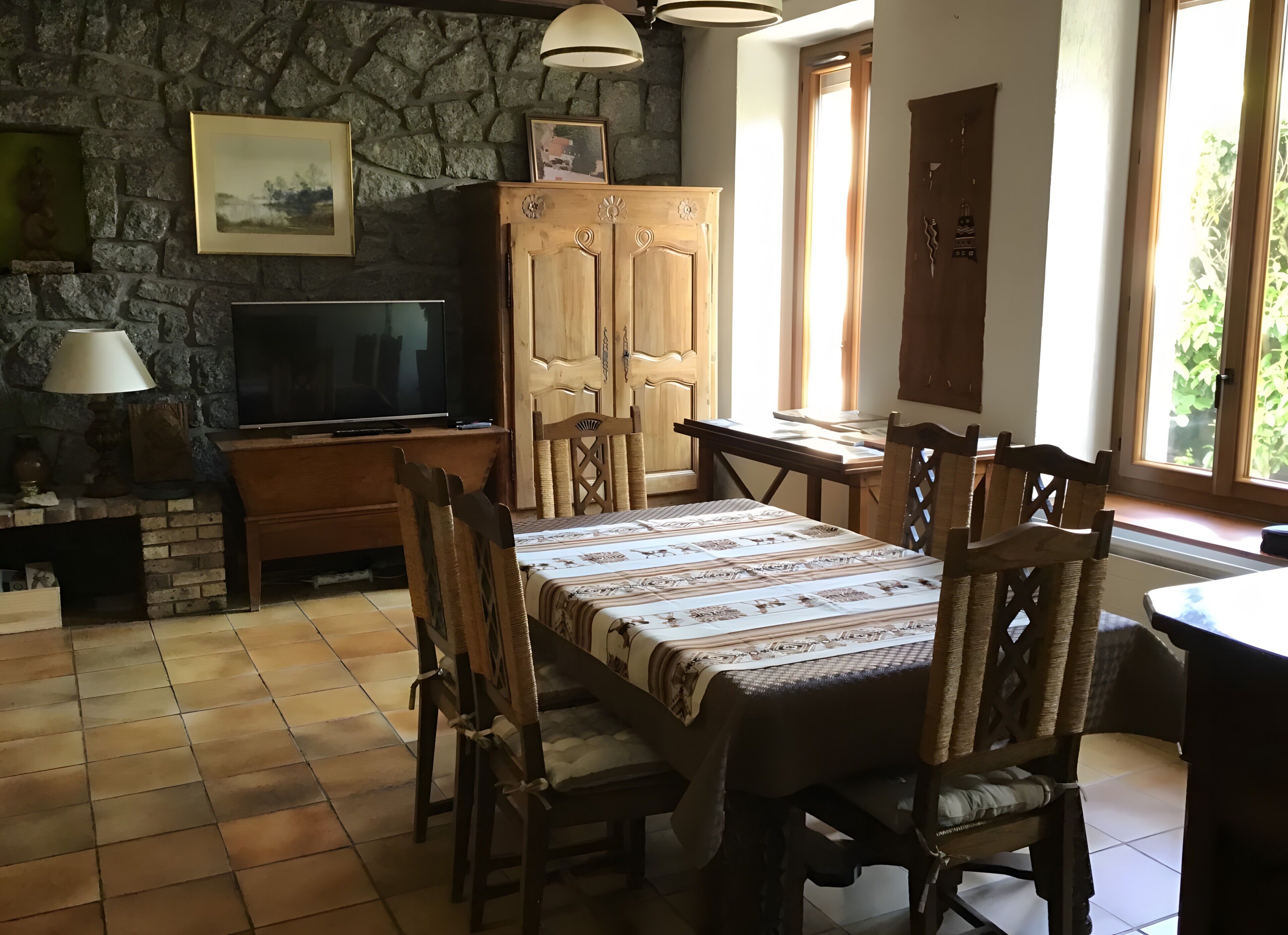 A cozy room with a stone wall, wooden furniture, a television, and a window with a view.