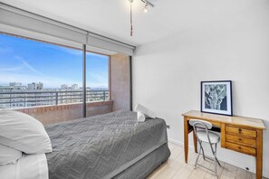 Quarto com cama, escrivaninha e cadeira.