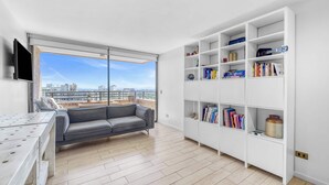 A modern living room with a sofa, a bookshelf, and a TV.