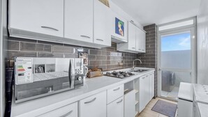 A modern kitchen with white cabinets, a stainless steel range, and a large window.