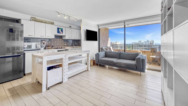 A modern kitchen with a built-in oven, a coffee machine, and a TV mounted on the wall.