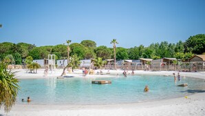 Une plage avec une eau cristalline, des palmiers et des cabanes de plage.