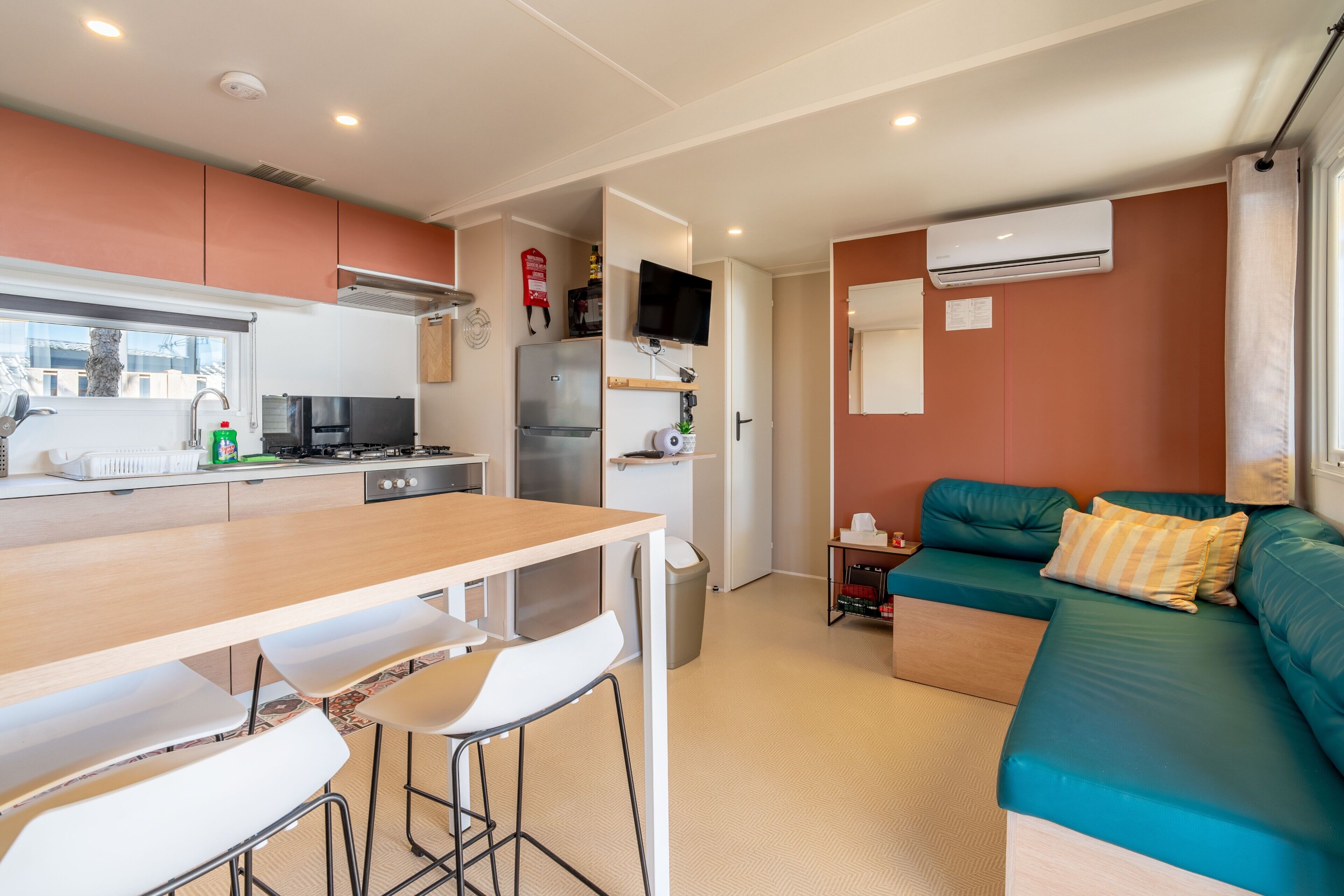 A compact living space with a kitchenette, a dining area, a sofa, and a TV.