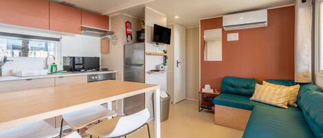 A compact living space with a kitchenette, a dining area, a sofa, and a TV.