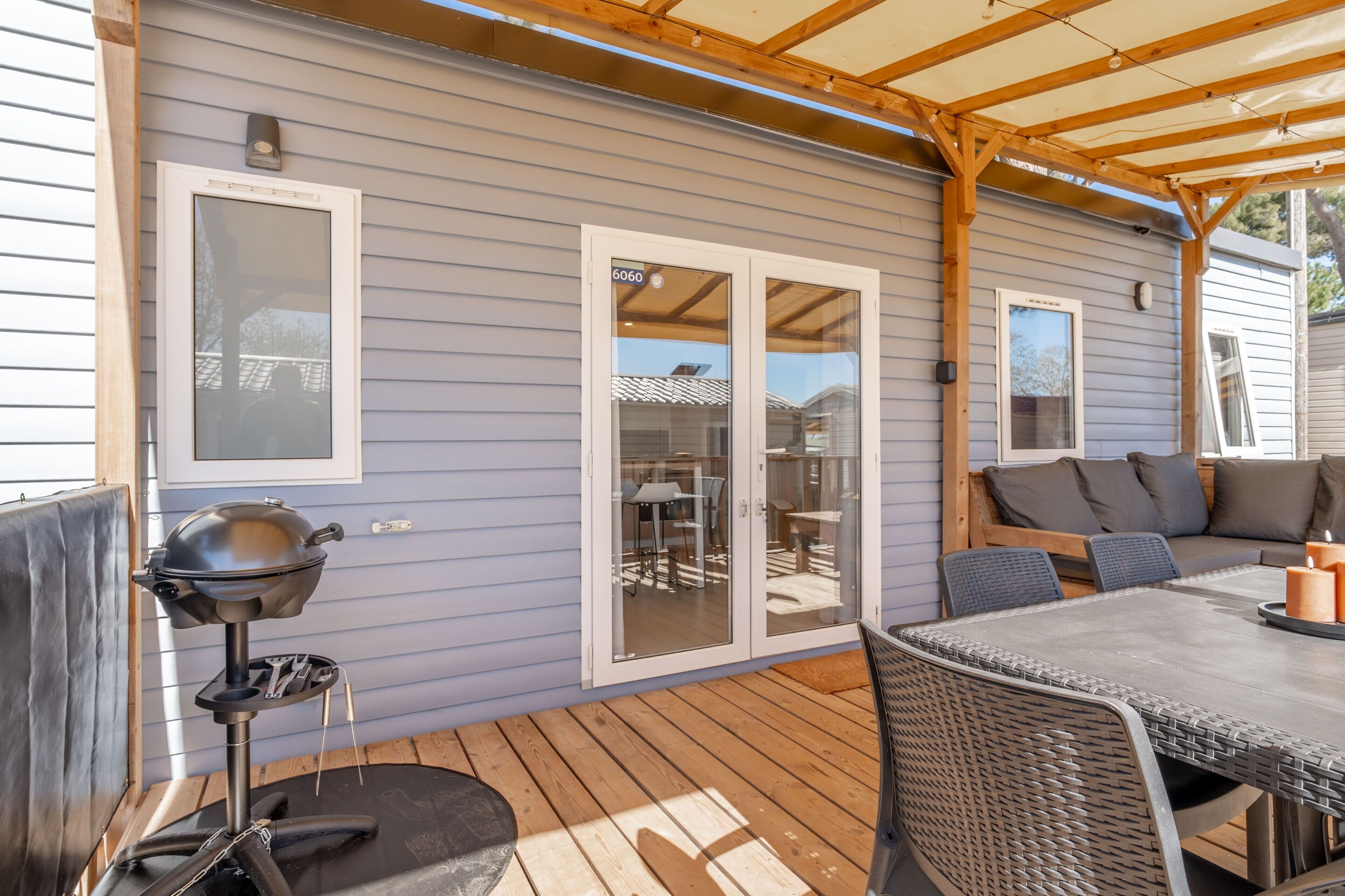 A covered patio with a grill, a table with chairs, and a sliding glass door leading to an outdoor area.