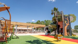 Une aire de jeux avec un toboggan, des structures d’escalade et un espace de repos abrité.