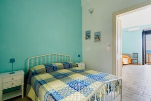A bedroom with a bed, nightstands, a window, and a door leading to another room. - Apartment 'Azzurra Home Holidays' with Sea View, Balcony and Air Conditioning (Nardò)