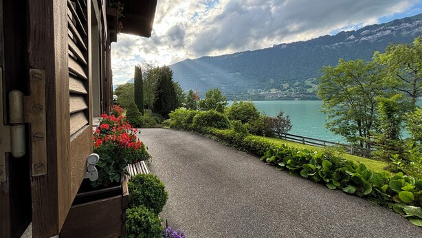 Uma entrada de cascalho leva a uma casa com vista para um lago e montanhas.