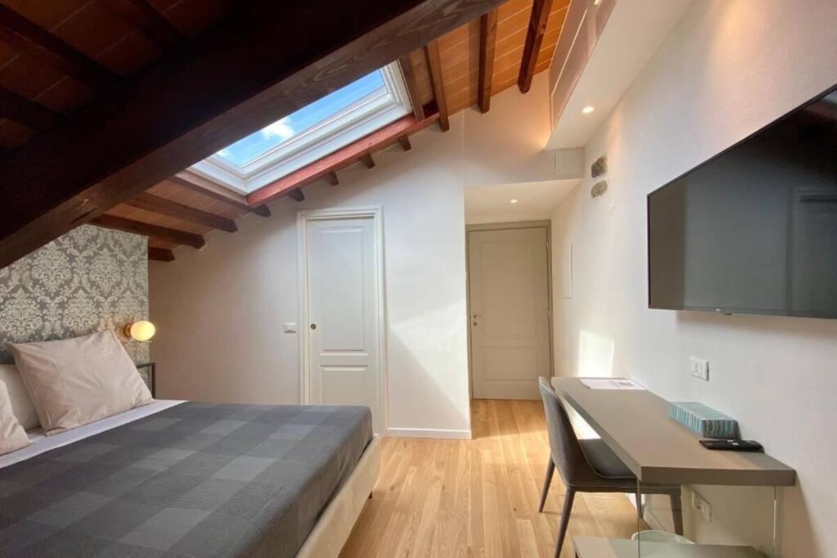 Ein Schlafzimmer mit Dachfenster, einem Bett, einem Schreibtisch und einem Fernseher.