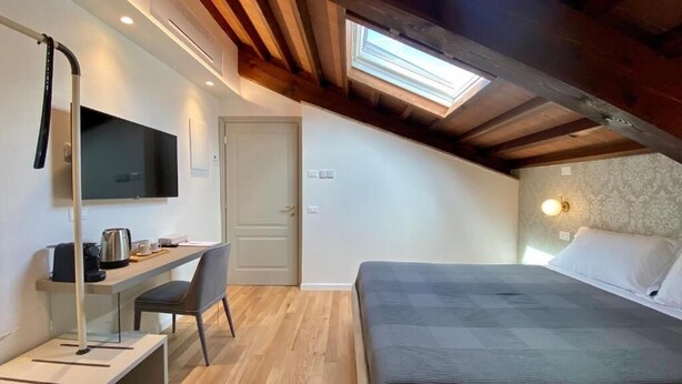 Une chambre à coucher avec un lit, un bureau et une chaise, une télévision et une lucarne.