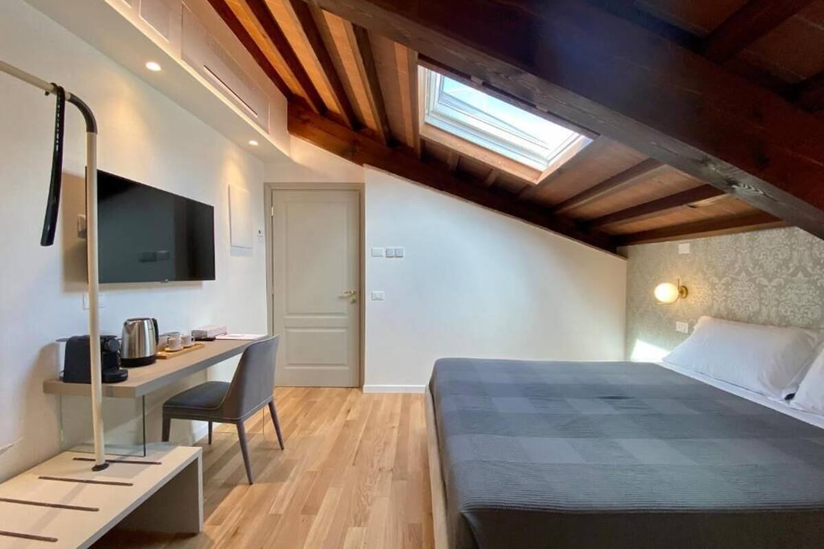Ein Schlafzimmer mit einem Bett, einem Schreibtisch mit Stuhl, einem Fernseher und einem Oberlicht.