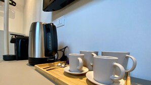 Un comptoir de cuisine avec une machine à café, quatre tasses blanches et un plateau.