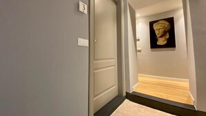 Un couloir avec une porte portant le numéro « 3 », un interrupteur et une œuvre d’art encadrée accrochée au mur.